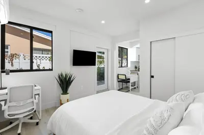 a white bedroom with a bed and a desk and a chair at Mango House en Dania Beach in Dania Beach