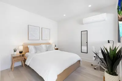 a white bedroom with a bed and a potted plant at Mango House en Dania Beach in Dania Beach