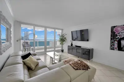 a white living room with a couch and a television at Ray of Light! Miami Penthouse! in Miami