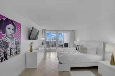 a white bedroom with a white bed and a television at Ray of Light! Miami Penthouse! in Miami