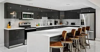 a kitchen with a large white island with bar chairs at Miami's Exclusive Lagoon Villa in Miami