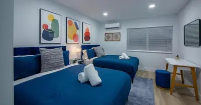 a blue bedroom with two beds and a table at New Oasis Waterfront & Sand Terrace THG in Miami