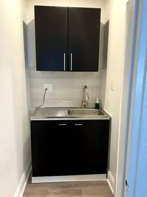 a kitchen with a sink and black cabinets at Nice and Cozy guest house in Miami