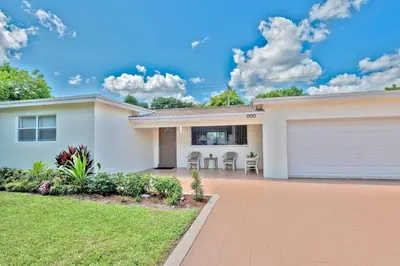 a house with a garage and a lawn at Luxurious 5 bedrooms Jacuzzipool in Miramar