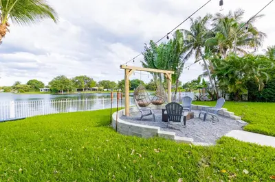 a group of chairs sitting on a patio by the water at Lakefront Villa and Paddle Board TGH in Miami