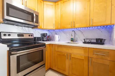 a kitchen with wooden cabinets and a stove and microwave at Vista Mar: Bay Views Close to Miami Attractions in Miami Beach