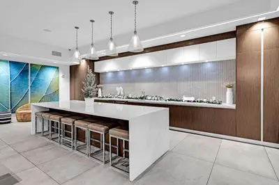 a kitchen with a large white counter and stools at Modern 1 Bed in Downtown Doral With Free Parking in Hialeah Gardens