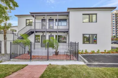 a white house with a wrought iron gate at 2 Condo Combo - Walk to Beach Off Las Olas 1AB in Fort Lauderdale