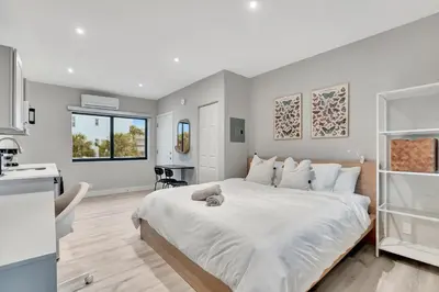 a bedroom with a large white bed and a kitchen at Studio Right off Las Olas - Steps to FTL Beach 2B in Fort Lauderdale