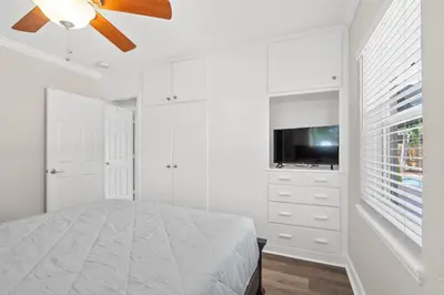 a white bedroom with a bed and a flat screen tv at Wills off Wilton Drive 2 bed and 1 bath plus Den with Heated Pool in Fort Lauderdale