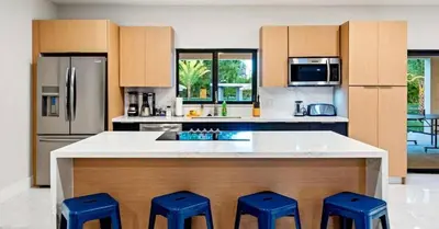 a kitchen with a large island with four blue stools at Sunny Isles Beach Luxury Property by Glam Homes in Miami