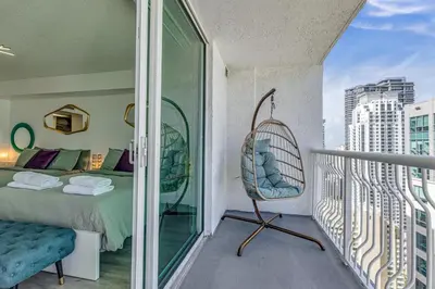 a room with a bed and a swinging chair on a balcony at Oceanside Penthouse Apartment in Brickell Miami, Pool, Free Parking in Miami