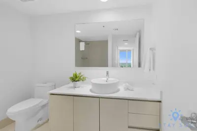 a bathroom with a sink and a toilet and a mirror at Modern Resort Retreat Steps from the Beach in Hallandale Beach