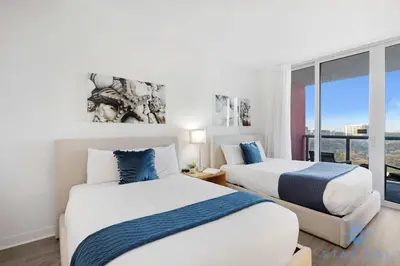 two beds in a room with a window at Modern Resort Retreat Steps from the Beach in Hallandale Beach