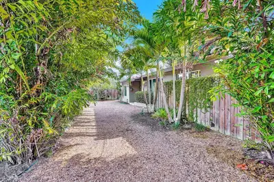 a house with a fence and trees in front of it at Heated pool, parking, 5 min walk to food and fun! in Fort Lauderdale