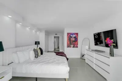 a white bedroom with a white bed and a tv at Shades of Miami Sky Penthouse! Newly Renovated in Miami