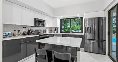 a kitchen with a white counter and a stainless steel refrigerator at Entertaining Villa Fun Games Mini Golf Grill in Miami