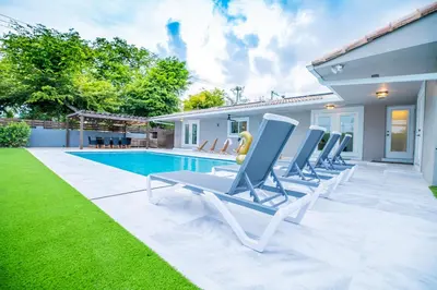 a row of lounge chairs next to a swimming pool at Villa w/a Huge Terrace & Grill Mini Golf Pool in Miami