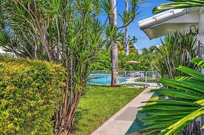 a swimming pool with palm trees and a garden at 1 bedroom tropical pool house in Hallandale Beach