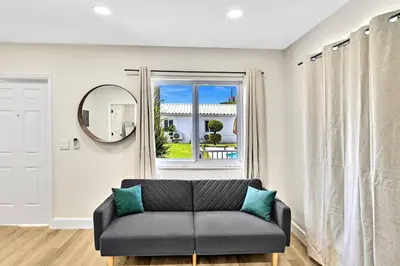 a living room with a couch and a mirror at 1 bedroom tropical pool house in Hallandale Beach