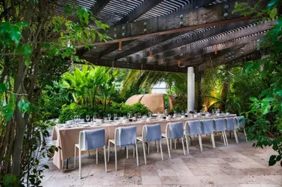 a long table with chairs in a garden at CasaGrandeSouthBeach by AmericanVacationLiving 6BR in Miami Beach