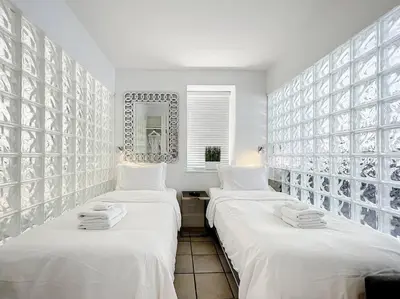 two beds in a room with white walls at CasaGrandeSouthBeach by AmericanVacationLiving 6BR in Miami Beach