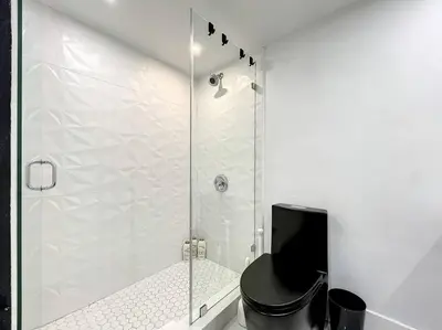 a bathroom with a shower with a black toilet at CasaGrandeSouthBeach by AmericanVacationLiving 6BR in Miami Beach