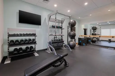 a gym with a bench and a flat screen tv at Tru By Hilton Miramar in Miramar