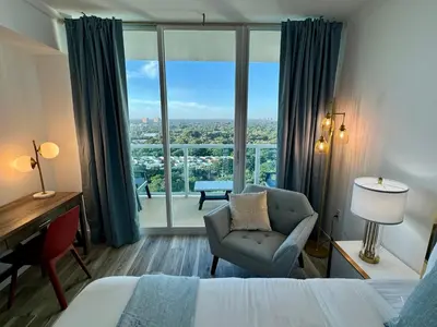 a hotel room with a bed and a chair and a window at Balcony Ocean View ! Pool - WiFi - Gym - Parking in Miami