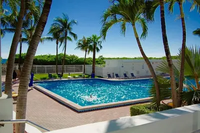 a swimming pool with palm trees in a resort at Directly on the Beach with Pool & Ocean View in Miami Beach