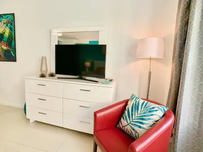 a living room with a red chair and a tv at Directly on the Beach with Pool & Ocean View in Miami Beach