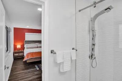 a bedroom with a bed and a glass shower at Gorgeous poolhome on the canal in Fort Lauderdale