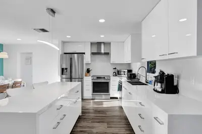 a white kitchen with white cabinets and appliances at Gorgeous poolhome on the canal in Fort Lauderdale