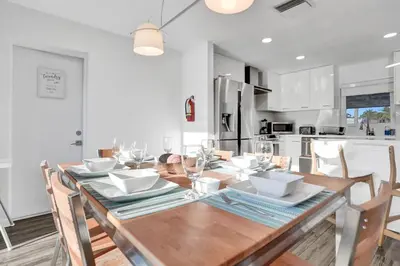 a dining room with a wooden table and a kitchen at Gorgeous poolhome on the canal in Fort Lauderdale