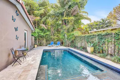 a swimming pool in a backyard with two chairs and a table at 3bed 2bath with pool, 5 min. walk to food and fun in Fort Lauderdale