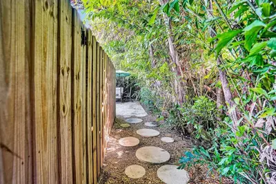 a wooden fence next to a path next to a forest at 3bed 2bath with pool, 5 min. walk to food and fun in Fort Lauderdale