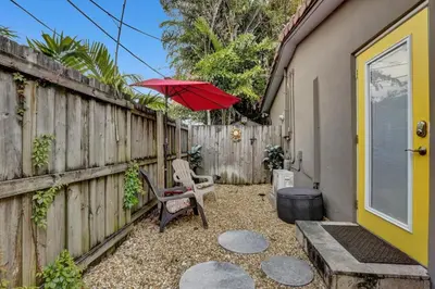 a patio with a fence and a red umbrella at Private studio, 5 min. walk to Wilton Drive in Fort Lauderdale