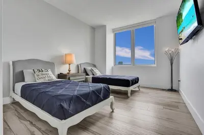 a bedroom with a bed and a flat screen tv at Lower Penthouse 3BD 3BA Beach Gym and Pool in Hallandale Beach