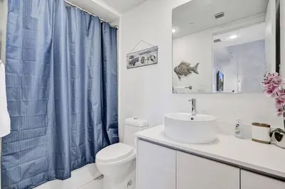 a bathroom with a blue shower curtain and a sink at Upscale Resort 4 Bedrooms 3 bath in Hallandale Beach
