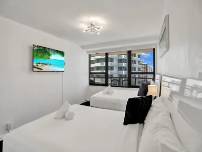a white bedroom with two beds and a window at Beautiful condo in resort beach service 1004 in Miami Beach