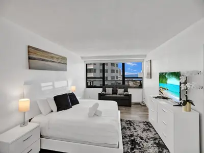 a white bedroom with a white bed and a tv at Beautiful condo in resort beach service 1004 in Miami Beach