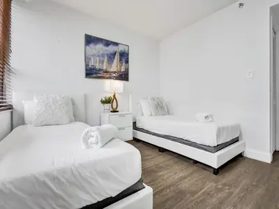 two beds in a bedroom with white walls and wood floors at Amazing Ocean View Condo Beach Service 607 in Miami Beach