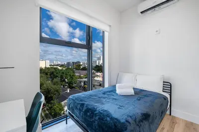 a bedroom with a bed and a large window at Pastel Apartments in Miami