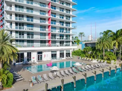 a resort pool with lounge chairs and a large building at Resort Near Beach with Amazing Pool and Gym in Hallandale Beach