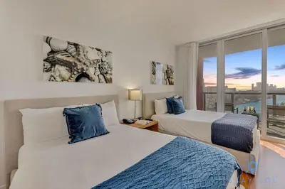 a bedroom with two beds and a window with a view at Beachwalk - Sun, Amazing Pools and Gym in Hallandale Beach