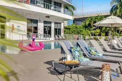a swimming pool with lounge chairs and a table and an umbrella at Beachwalk - Sun, Amazing Pools and Gym in Hallandale Beach