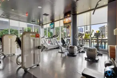 a gym with several treadmills and chairs and windows at Beachwalk - Sun, Amazing Pools and Gym in Hallandale Beach