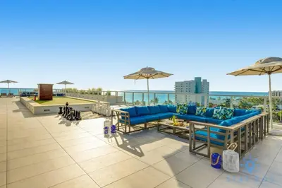 a patio with blue couches and umbrellas on a roof at Front Bay View, Enjoy Sunsets, Amazing Pool in Hollywood