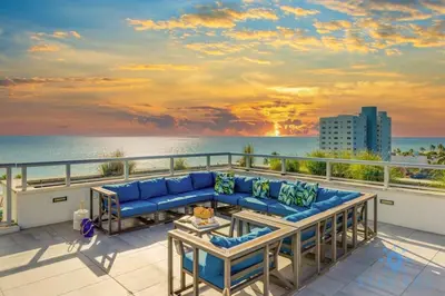 a living room with a couch on a balcony overlooking the ocean at Worth Traveling Hot tub & Unique Rooftop pool in Hollywood