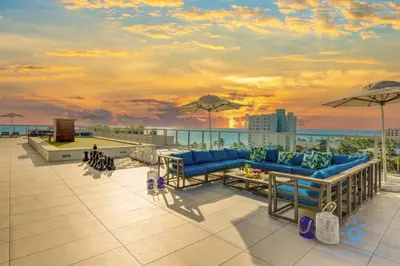 a patio with blue couches and umbrellas on a roof at Rooftop Pool & Hot Tub Hollywood Beach Gym in Hollywood